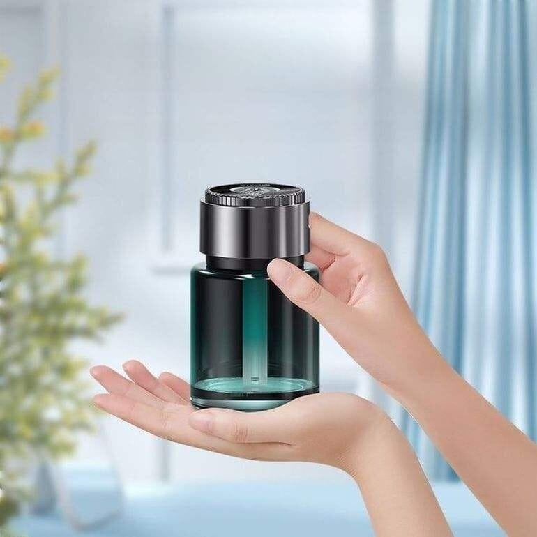 Auranza Cart smart car perfume diffuser held between two hands with black top and transparent bottle